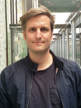 Porträt von Janko Grode mit blauer Jacke vor einem langen Gang.