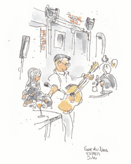 Zwei Musiker:innen stehen vor einer alten Industriehalle und machen Musik. Ein Mann mit Schiebermütze spielt Gitarre. Eine Frau mit geblümtem Hemd hält ein Mikrofon in der Hand und singt.
