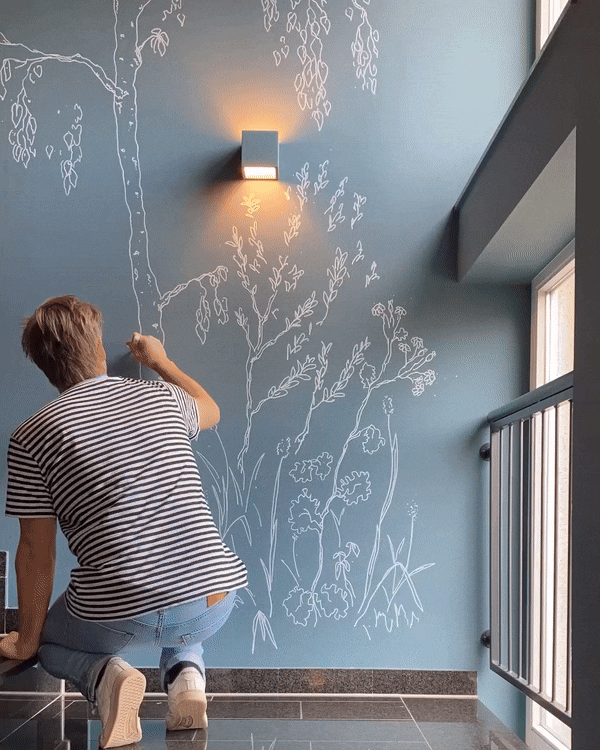 Janko Grode zeichnet Pflanzen an die Wand im Hotel Das Lola 